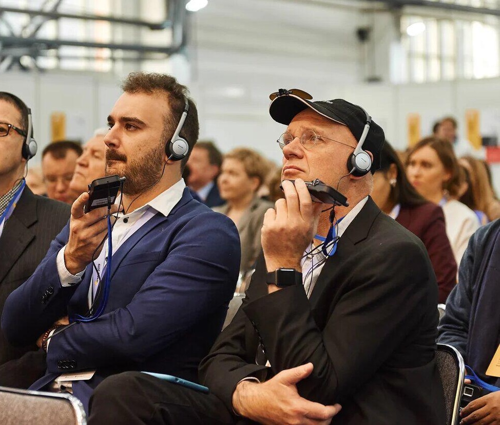 Two men at a conference, using headphones to listen to the speech