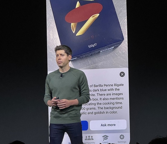 Sam Altman, CEO of OpenAI presenting on stage in front of image showing Be My Eyes app and our use of AI to describe images